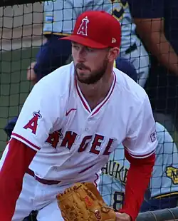 A man in a white baseball uniform with red undersleeves and cap