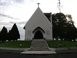 A square with small pine trees with a staircase leading to a chapel
