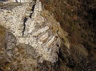 Square of half-high walls above a precipice. The wall that gives into the void is no longer there.