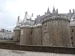 Colour photograph of the ramparts and towers of a castle in the middle of the city.