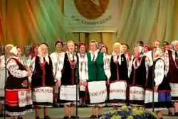 A group of elderly women in traditional costumes singing