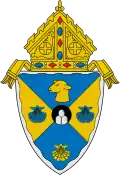 The arms of the Diocese of Rockville Centre: The mounds in the circle at the center of the arms are a play on the name of city in which the diocese is based, Rockville Centre, New York.[8]