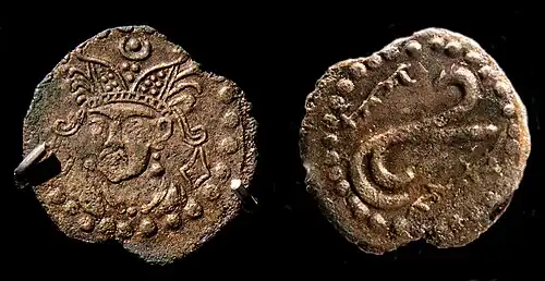 Coin in the name of Rakhanch, lord of Ushrusana. Tamgha symbol on the reverse with name of the ruler in Sogdian rγʾnč MRAY "Raxānič Afšīn".[1] Excavated in the Palace of Kala-i Kakhkakha I, Bunjikat. 7th century CE, National Museum of Antiquities of Tajikistan (RTL 213).[2] of Ushrusana