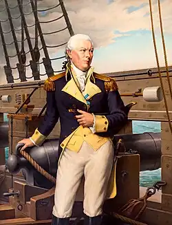 A color portrait of a male naval officer standing next to a cannon on a ship