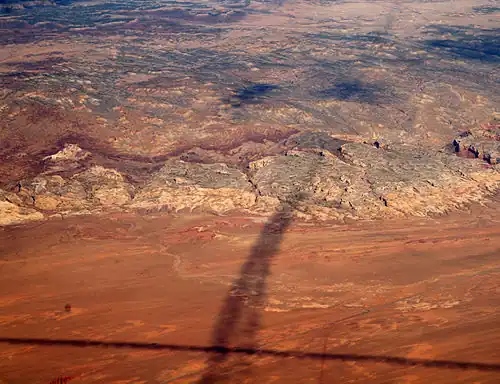 Shadows of contrails over San Rafael Reef — San Rafael Swell, Reef (perimeter), and San Rafael Desert at south & southeast. The Reef is most of the southeast, and east perimeter of the 45-mile-wide (72&nbsp;km) (west-to-east) San Rafael Swell, which trends southwest-by-northeast.