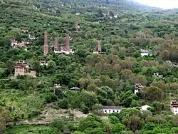 Village with tall watchtowers on a mountain slope with trees