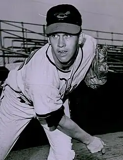 A man in a light baseball uniform and dark cap