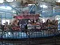 Side view of a historic carousel with a metal fence in the foreground