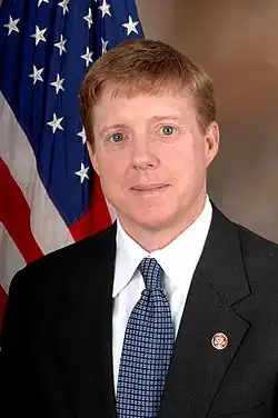 Official government portrait of Cazayoux standing in front of an American flag. He is a middle-aged white man with blue eyes and blond hair, wearing a morning suit.