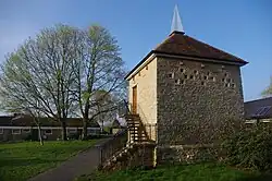 Photo of old dovecote, boxes converted to windows, sharp spike on top, and modern concrete stairs added externally