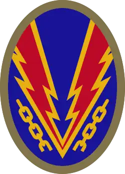 Oval shaped shoulder patch with a deep blue background. Lightning bolts break a yellow chain, representing the liberation of Nazi-occupied Europe.