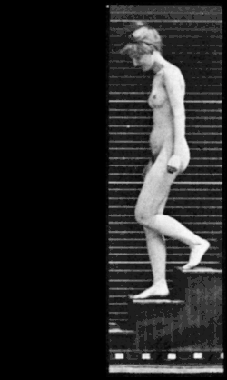 Greyscale: a nude woman walks down stairs then turns left