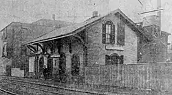 A two-story wooden railway station in an urban area