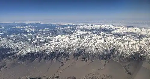 Aerial view from the east of the Eastern Sierra with Mount Whitney. The snow-capped mountains drop steeply to dry desert on the east side.