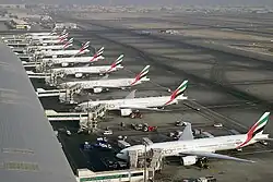 View of airport terminal building with 10 airliners parked in a row adjacent to it.