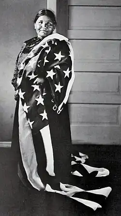 full length photograph of a Native American woman wrapped in an American flag