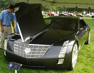 Man looking at Cadillac Sixteen with open hood.The car has hotwheel of it to