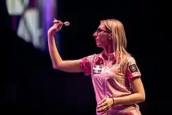 A side profile of Fallon Sherrock throwing a dart