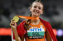 Photo of Femke Bol from her waist up holding up her gold medal