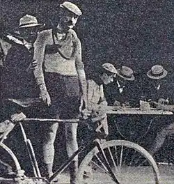 Image of a man in cycling gear standing behind a bike