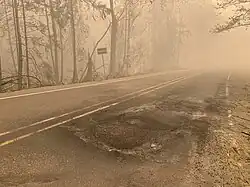 A smoky scene on a rural two-lane highway with ash and debris on the road surface