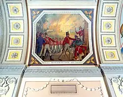 A painting depicting British soldiers, wearing red, fighting with another army. Behind them, a fire burns. The painting is outlined by a white hexagon.