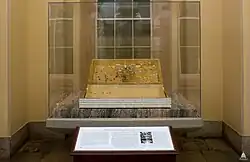 A glass box that holds a replica Magna Carta. Behind the display is window, and an informational plaque is in front of the display.