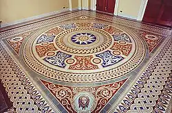 A floor with several tiles in colorful circular patterns. In the middle of the floor is a depiction of the sun.