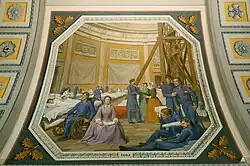 A painting that depicts the Rotunda during the Civil War, during the six-week period that it was used as a hospital. A woman is sitting next to injured soldiers, reading a book.