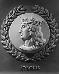 A grey marble sideview of Saint Louis. He is looking to the left, and is wearing a crown. Surrounding the circular frame is a laurel wreath. Under the engraving is the text "ST. LOUIS".