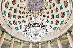 A colorful domed ceiling with a semi-circular chandelier hanging from its highest point.