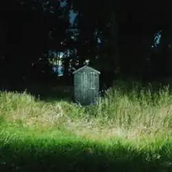 An outhouse in a field of long grass
