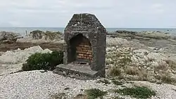 A decaying stone furnace on a wide rocky beach