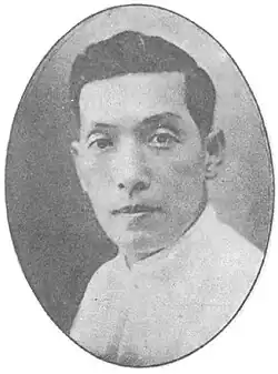 A black-and-white picture of a man, looking forward. He is wearing a white shirt.
