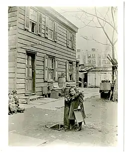 Unidentified girl at the water pump at the rear of 65 E. 87th Street, north side between Madison and Park, New York City, April 21, 1898