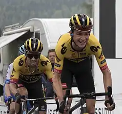 Kuss riding out of the saddle in a yellow jersey ahead of teammate Primož Roglič