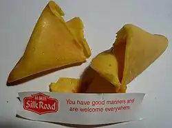 An opened fortune cookie, with the printed fortune that was inside it