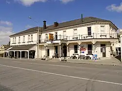 An old-fashioned two-storey hotel with a grey tile roof and tan walls