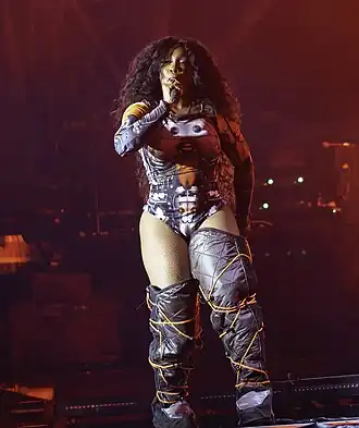 SZA in knee-high boots and a robot-design bodysuit, performing within red lights