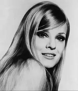 A woman with long blonde hair glancing over her right shoulder