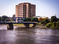 A nine-story campus building with Grand Valley State University signage as seen from the opposite side of a river