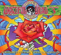 The hand of a skeleton holding a large rose, with radiating orange lines. In the background are the silhouettes of several tall buildings.