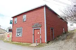 photo of a two-storey wooden building, covered with red clapboard.