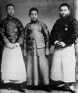 A black and white photo of three adolescent men standing together.