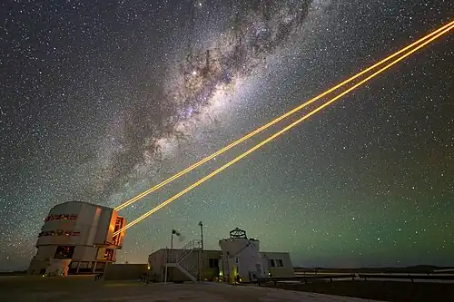 A telescope emitting four orange laser beams