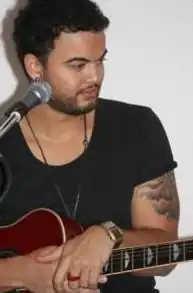 A man wearing a black shirt, holding a guitar