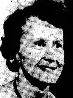 A smiling white woman of about sixty years, with short dark hair in a set style