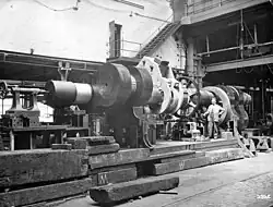 Finishing the ends of a crankshaft after building;[119] an improvised lathe for machining a large steam engine crankshaft, 1900[80] with a worm and wheel for turning the shaft in the centre. In the background on the far right is a screw cutting machine.[120]