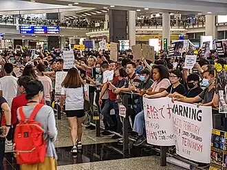 Protesters handing leaflets and showing signs to tourists arriving in Hong Kong