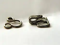 A hook-and-eye clasp is composed of two pieces that are sewn to clothing, one of which serves as a hook while the other as a staple